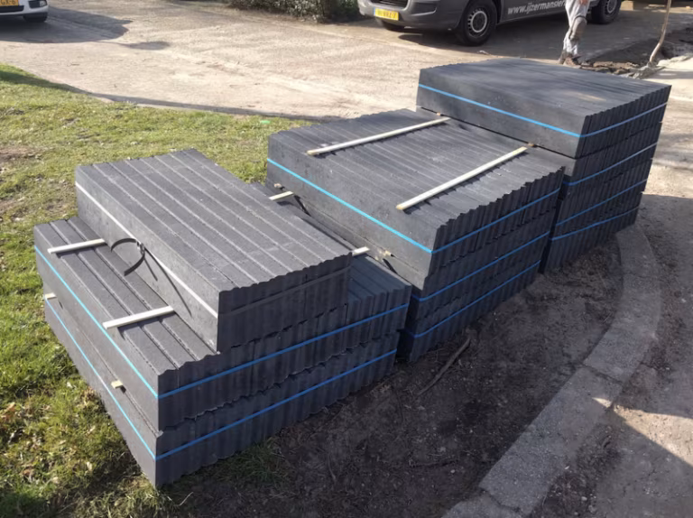Pallets met zwart antraciet opsluitbanden en blauwe spanbanden op gras