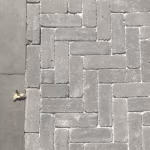Visgraatverband van Tambour Antraciet naast grijze betontegels, bovenaanzicht
