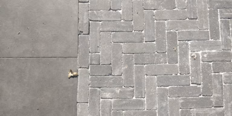 Visgraatverband van Tambour Antraciet naast grijze betontegels, bovenaanzicht