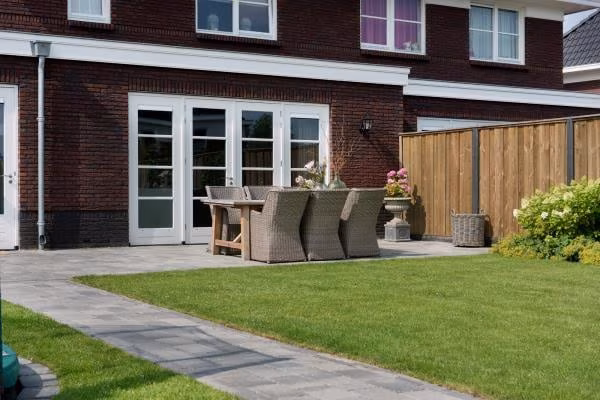 Tuin met gazon, pad en terras van Tambour Smook bestrating bij bakstenen woning
