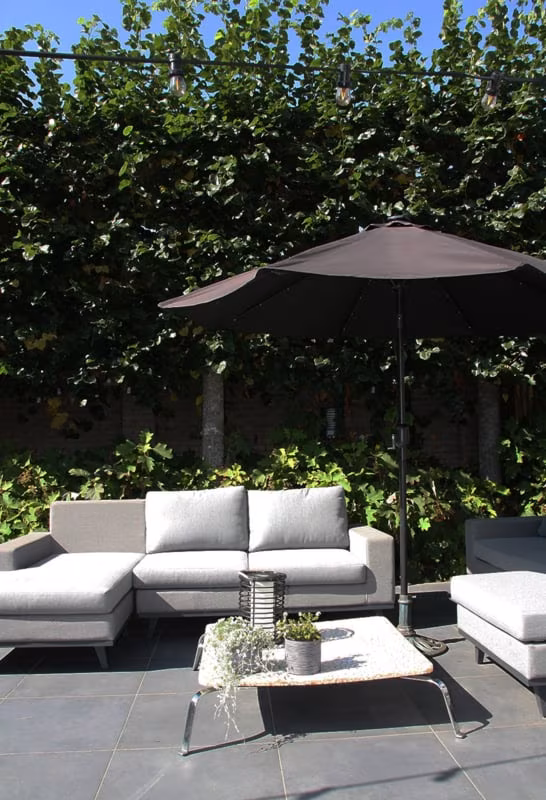 Loungeset met parasol op Kera Full Body Leuven tegels voor hoge haag