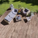 Terras van Timber Noce houtlooktegels met rotan loungeset en plantenbak, schuin van boven