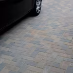 Oprit met Tremico BKK bont klinkers in grijsbruin patroon naast zwarte auto