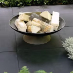 Zwarte Soft Comfort Nero tuintegels op terras met vuurschaal met haardhout en varens