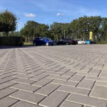 Groot parkeerterrein met grijze Tremico BKK klinkers in keperverband en geparkeerde auto's