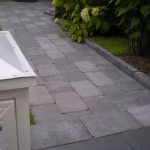 Pad van grijze Tambour Smook bestrating met opsluitband langs de border
