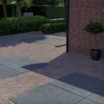 Oprit met antraciet Schellevis tegels tussen rood gebakken klinkers in visgraat, voor bakstenen woning