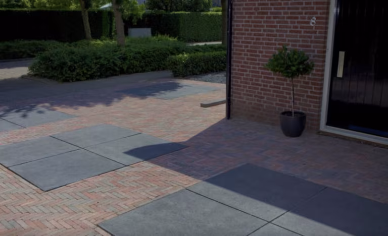 Oprit met antraciet Schellevis tegels tussen rood gebakken klinkers in visgraat, voor bakstenen woning