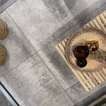 Bovenaanzicht Soft Comfort Grezzo tegels met schaal op bamboe tafel en voeten van persoon