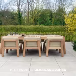 Teakhouten eettafel met stoelen op lichtgrijze Piet Boon Outdoor tegels naast heg