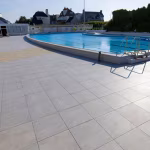 Zwembadterras met GeoCeramica Fiordi Sand tegels en huizen op de achtergrond