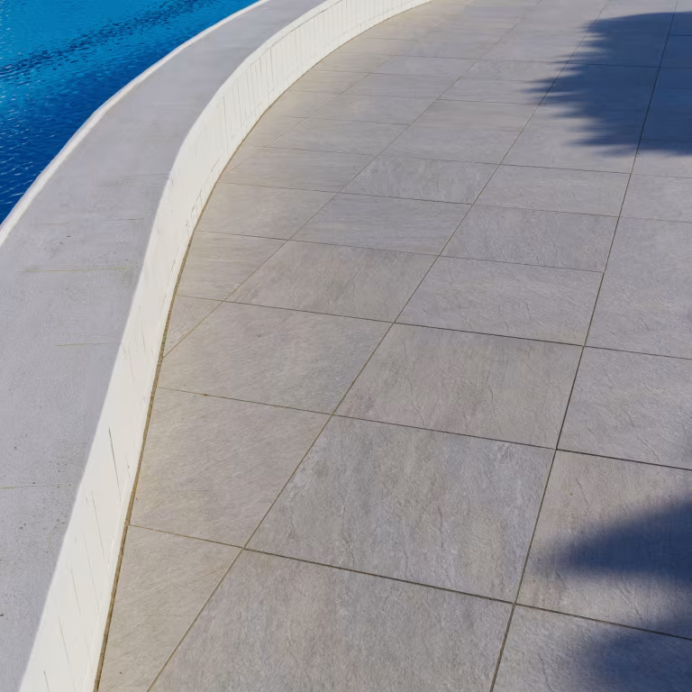 Gebogen zwembadrand met GeoCeramica Fiordi Sand tegels in schaduw en zon