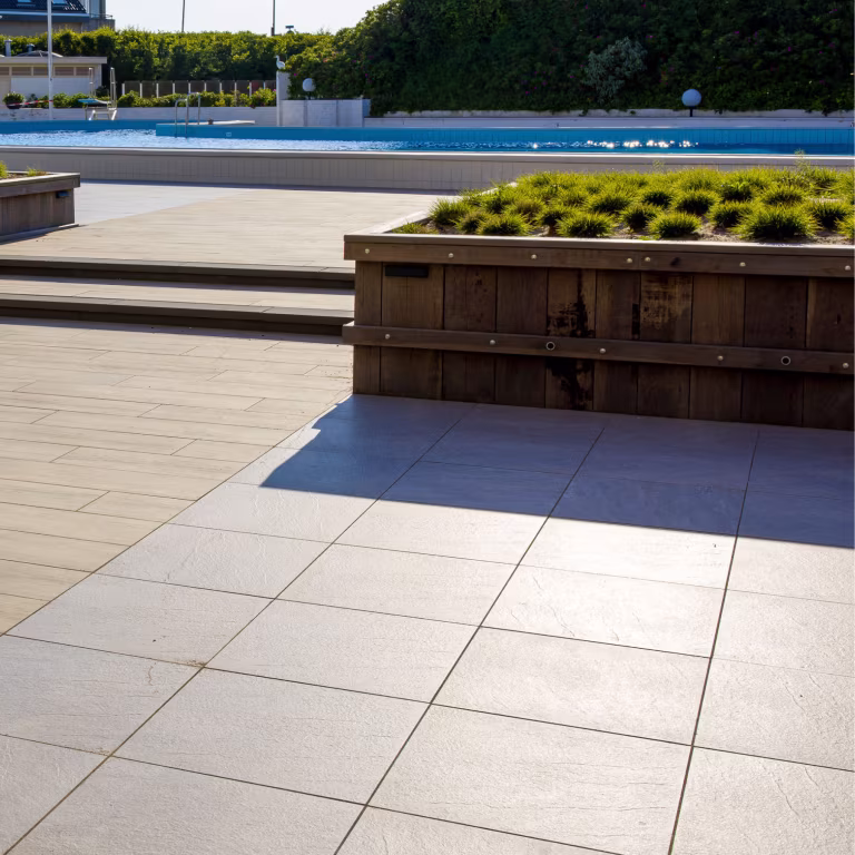 Zwembad met GeoCeramica Fiordi Sand tegels, houten plantenbak met siergras en trap