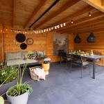 Overkapping met zithoek, eettafel, hanglampen en slingers op GeoCeramica Flow Black tegels