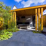 Zicht op houten overkapping vanaf GeoCeramica Flow Black tegels onder blauwe lucht