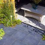 GeoCeramica Flow Black tegels naast overkapping met patroontegels en rotan salontafel