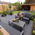 Tuin met loungebank, loungestoelen en salontafel op GeoCeramica Flow Black tegels, schuin van boven