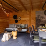 Houten overkapping met loungebank, eettafel en slingers op GeoCeramica Flow Black tegels