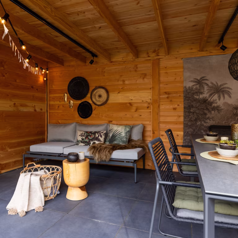 Houten overkapping met loungebank, eettafel en slingers op GeoCeramica Flow Black tegels