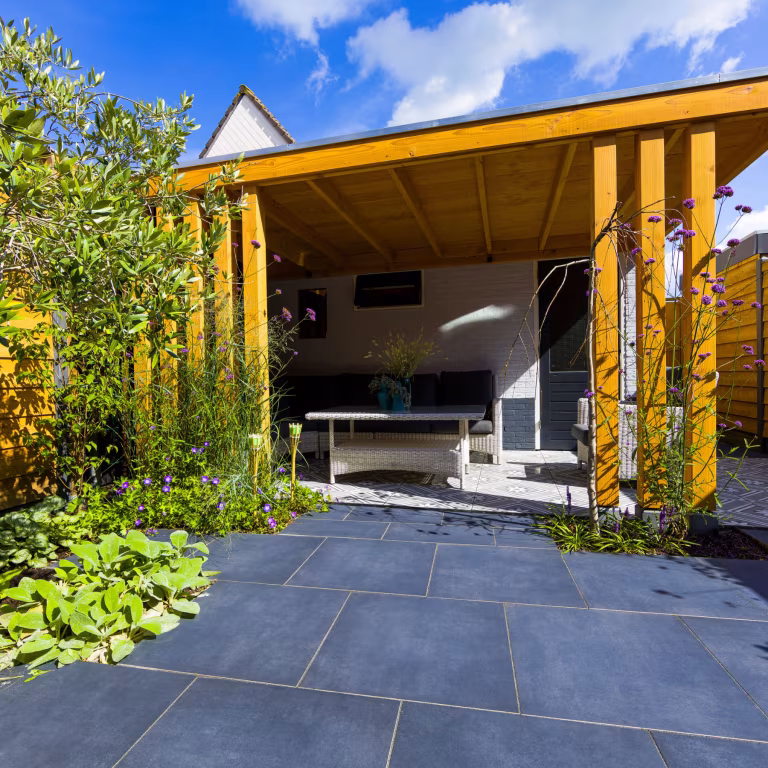 Zicht op houten overkapping vanaf GeoCeramica Flow Black tegels onder blauwe lucht