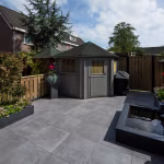 Terras met GeoCeramica Fumato Mezzo tegels, tuinhuisje, barbecue en vijver in stadstuin