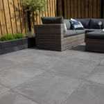 Rieten loungeset met kussens op GeoCeramica Fumato Mezzo terras bij houten schutting