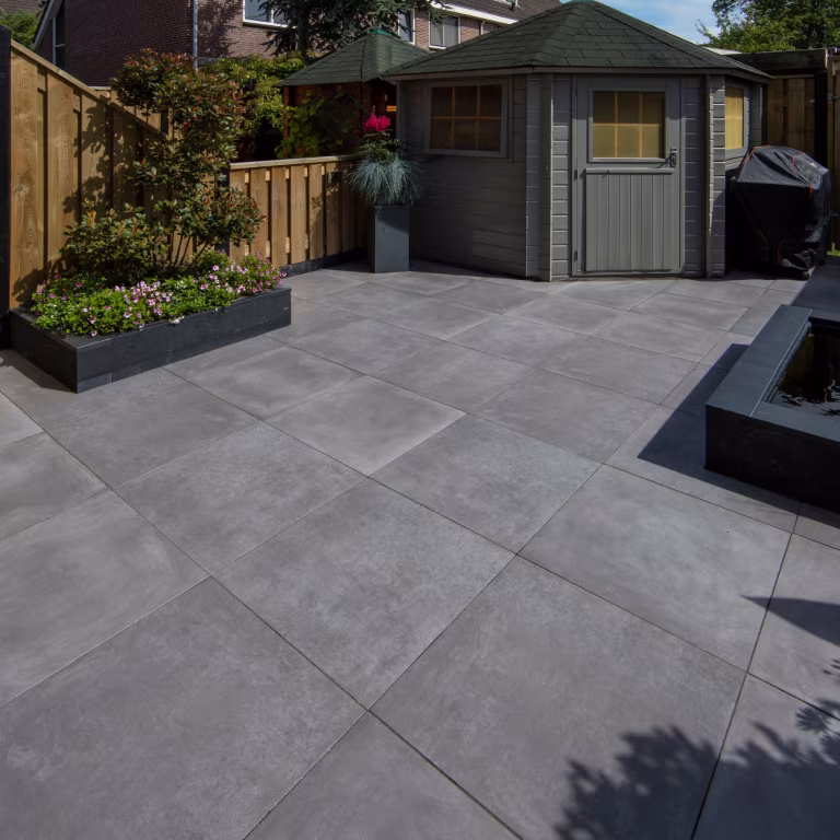 Ruim terras met GeoCeramica Fumato Mezzo tegels, plantenbak en grijs tuinhuisje
