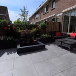 Achtertuin van rijtjeshuis met GeoCeramica Fumato Mezzo terras, vijver en loungemeubels