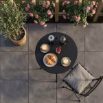 Bovenaanzicht terras met GeoCeramica Uros Plus Tar tegels, ronde tafel, croissants en rozen