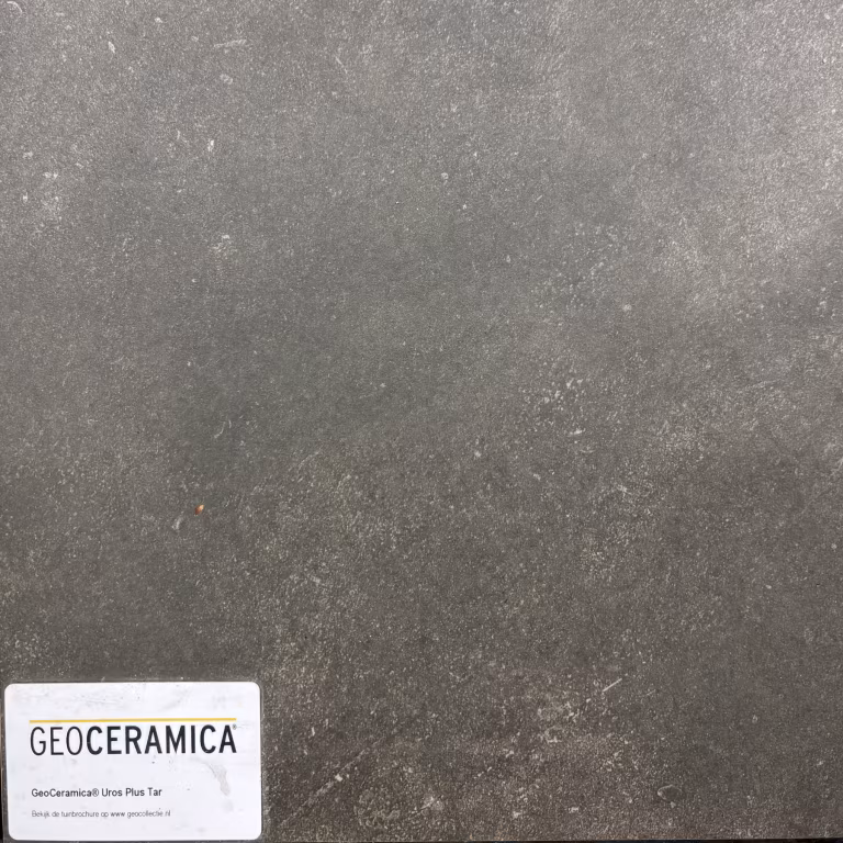 Close-up GeoCeramica Uros Plus Tar tegel met wit artikellabel linksonder