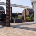 Houtlook terras Timber Noce langs afvoergoot met bakstenen pilaren en witte balk