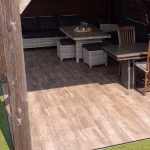 Rotan loungehoek met lage tafel op Timber Noce houtlooktegels onder houten overkapping
