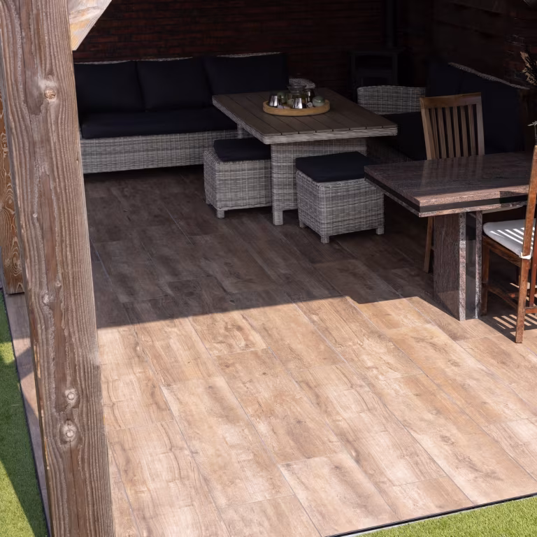 Rotan loungehoek met lage tafel op Timber Noce houtlooktegels onder houten overkapping