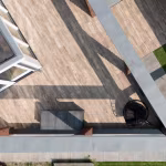 Drone-opname van Timber Noce terras met hangstoel, opbergbox en schaduw van dakrand