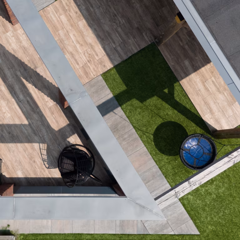 Drone-opname van Timber Noce terras met kunstgras, hangstoel en blauwe balansbal