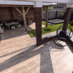 Houtlook terras Timber Noce met afvoergoot, overkapping, bakstenen pilaar en hangstoel
