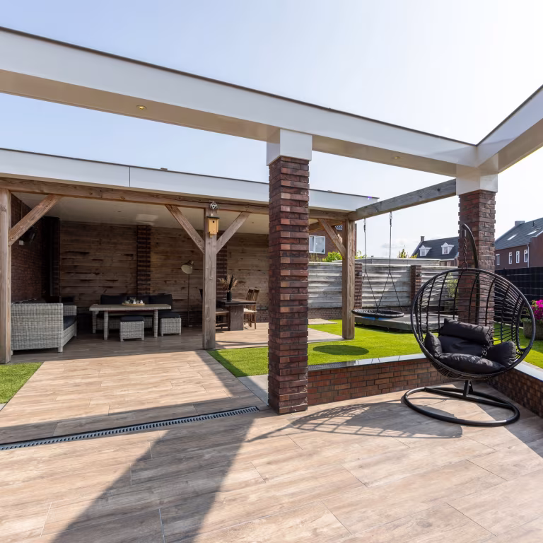Overkapping met terras van Timber Noce tegels, afvoergoot en hangstoel, brede hoek