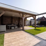 Overdekt terras met tuinset en Timber Noce tegels naast kunstgras en antraciete tegels