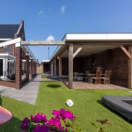 Tuin met kunstgras, voetbal en roze bloemen voor overkapping met Timber Noce vloer