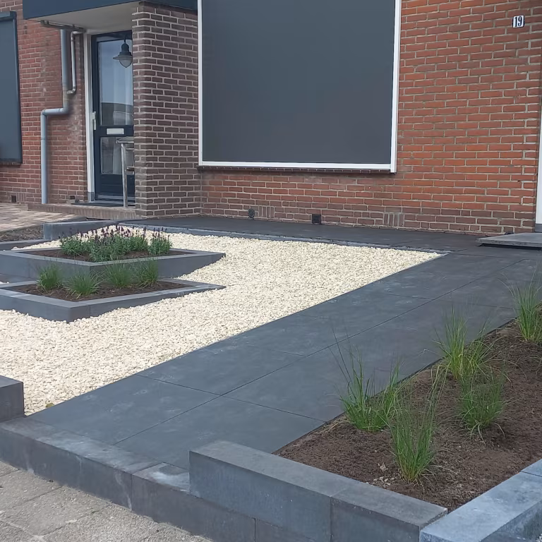Voortuin met pad van GeoCorso Catania tegels, wit grind en plantenbakken bij bakstenen woning