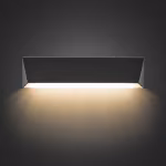 Brandende In-lite Wedge Slim wandlamp met warm licht naar beneden op donkere achtergrond