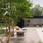Terras van Lotis klinkers met tuinset naast zwembad en zwart poolhouse