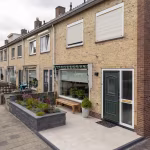 Rijtjeswoning met verhoogde plantenbak en bankje op terras van GeoCeramica Palanta Plus Gold tegels