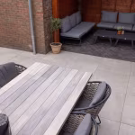 Loungehoek onder overkapping en houten eettafel op GeoCeramica Palanta Plus Gold terrastegels