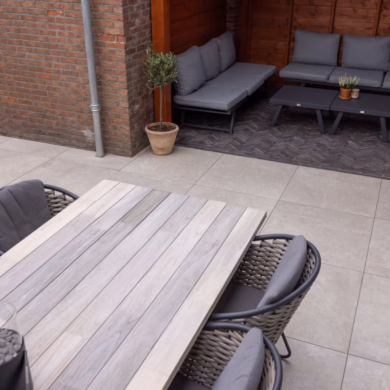 Loungehoek onder overkapping en houten eettafel op GeoCeramica Palanta Plus Gold terrastegels