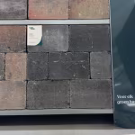 Showroomstaal Tambour Antraciet met Tuinvisie label naast bruinrode stenen