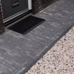 Pad van Tambour Antraciet waalformaat klinkers naar voordeur met deurmat en grindrand