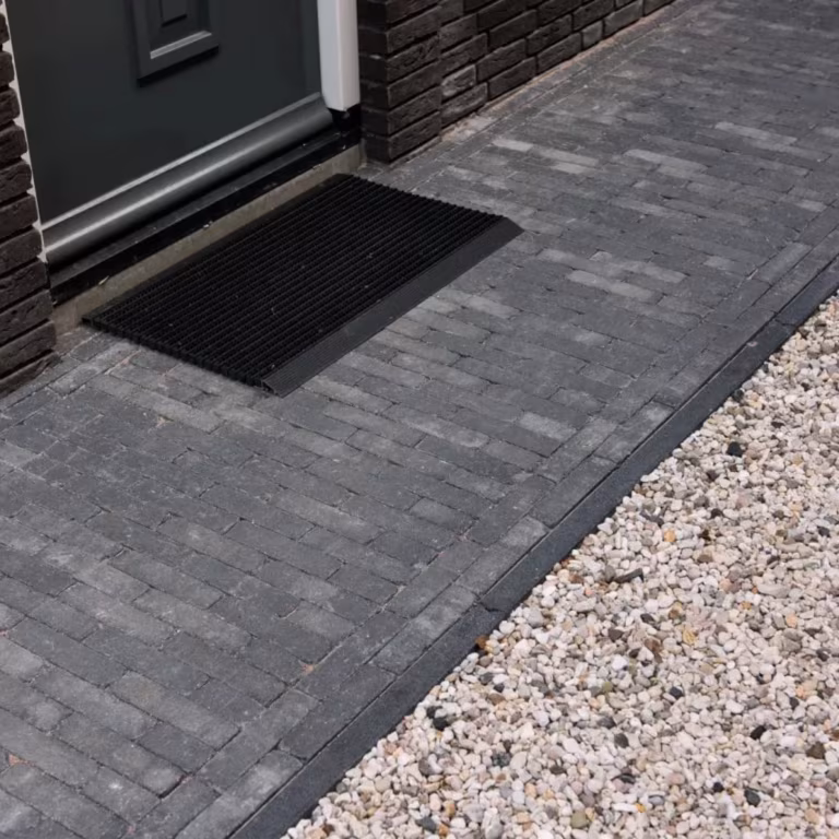 Pad van Tambour Antraciet waalformaat klinkers naar voordeur met deurmat en grindrand