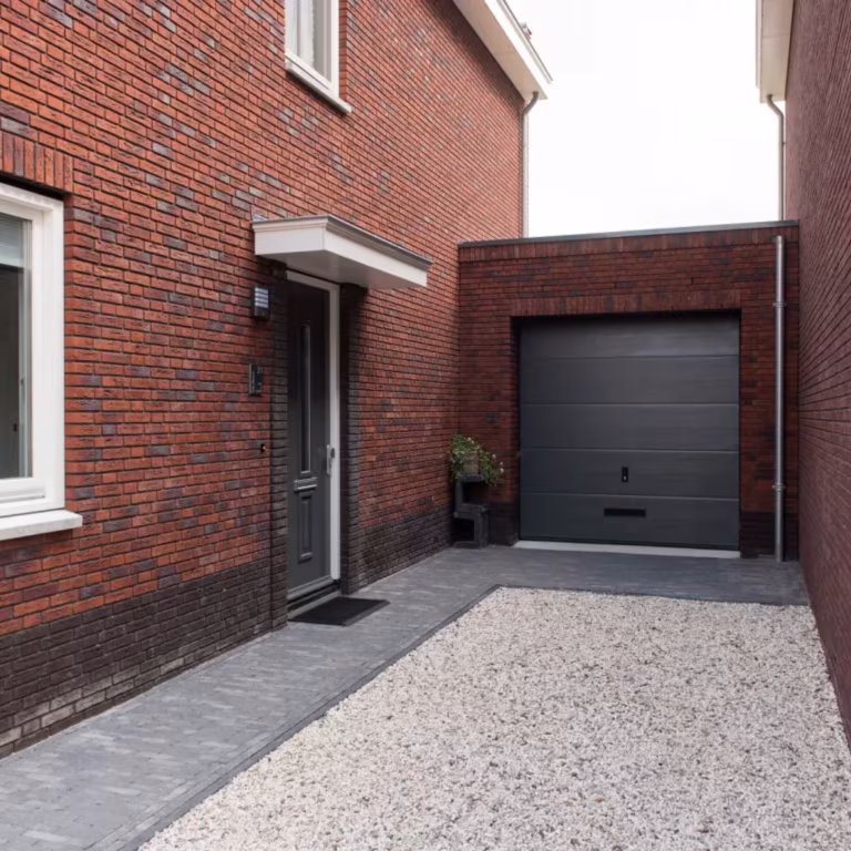 Woning met baksteengevel en garage, grindinrit met Tambour Antraciet waalformaat langs de gevel
