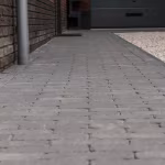 Oprit van antraciet Tambour waalformaat klinkers langs gevel en grindstrook